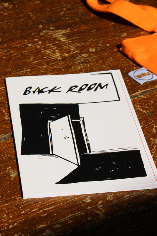 A square white notepad featuring a black hand-drawn illustration of a room with the words 'BACK ROOM' written vertically, placed on a rustic wooden surface.