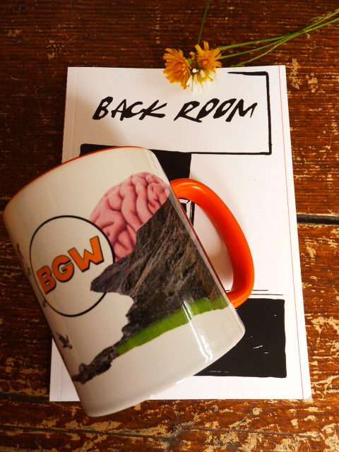 A white ceramic mug with an orange handle, rim, and inner colour. Featuring a collaged image, a graphic of a brain connected to a cliffside with the word 'BGW' in orange text. The mug is resting on a white art booklet with the words 'BACK ROOM' on a rustic wooden table next to a small yellow flower.